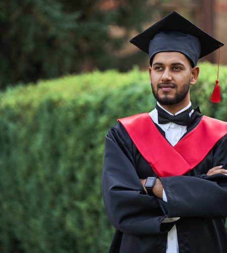 serious-indian-graduate-graduation-robe-with-crossed-arms-looking-forward-min